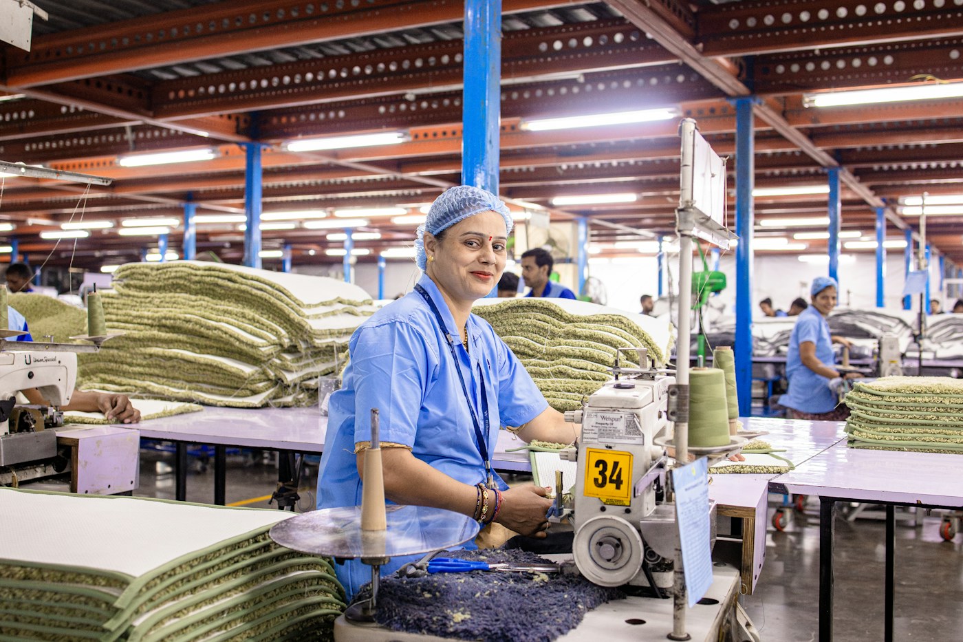 A textile worker at a sewing station on a factory production floor